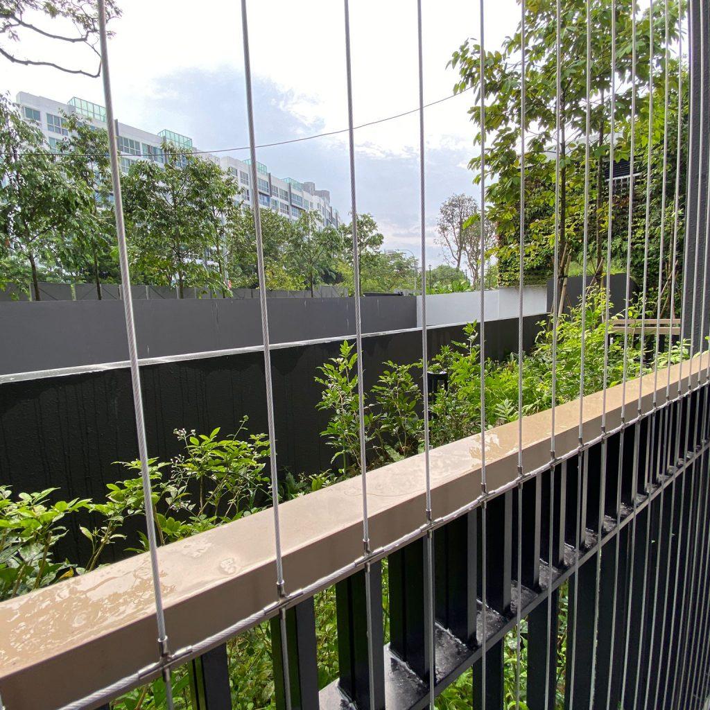 Balcony railing with invisible grill cables facing green trees